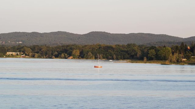 Small sailboat on Lake Maggiore near Ispra city at sunset