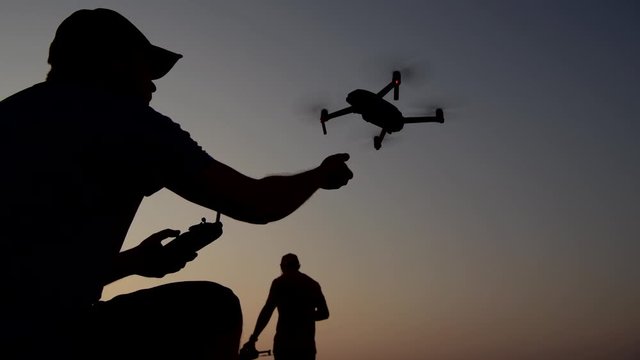 Drone Flying Field. Hobbies with Their Drone Aircrafts Flying During Scenic Sunset.