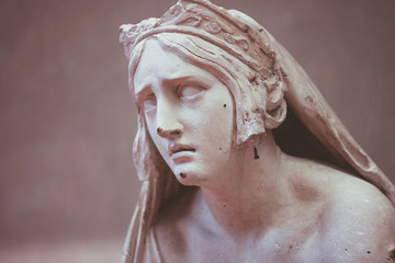 white statue of a  young woman with a sad face