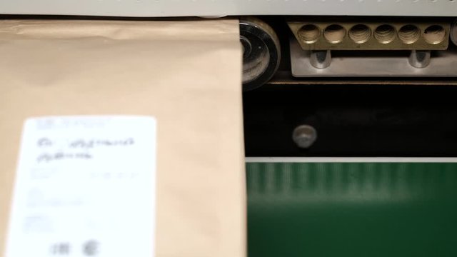 Close-up automatic bag sealing machine. Sealing packages with coffee.