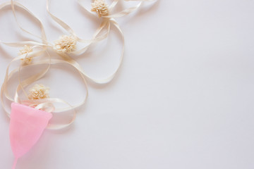 Menstrual cup with flowers on white background. Close up, flatlay