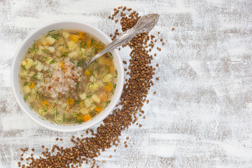 Top view of buckwheat soup in white bowl on white background