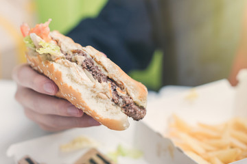  boy eating double cheeseburger. The concept of food and unhealthy lifestyle.