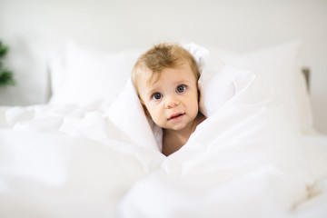 Cute happy baby girl in diaper on bed