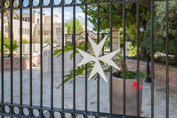 Cross of the Order of the Hospitallers on the fence of the Memorial Monument for Hospitaller hospital in the Old City in Jerusalem, Israel