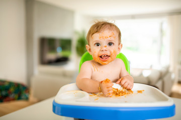 A Little baby eating her dinner and making a mess