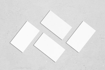 Four white rectangle business card mockups with soft shadows lying on grey concrete background....