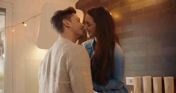 Young adult couple kissing together in the kitchen. Shot in slow motion	