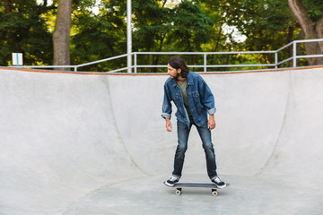 Handsome young hipster man skating on a skate ramp