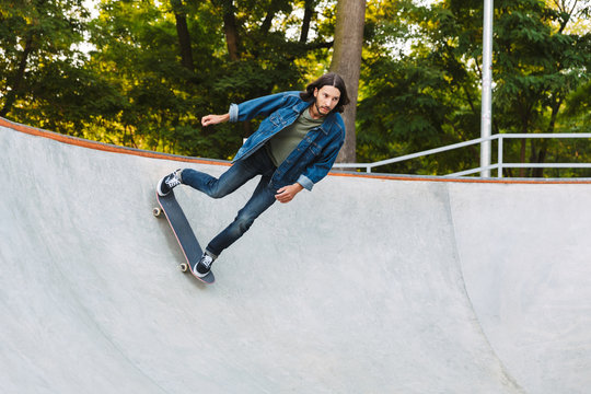 Handsome young hipster man skating on a skate ramp
