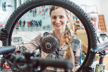 Fahrradmechanikerin schaut durch das Rad eines Fahrrads 