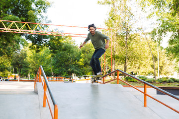 Fototapeta premium Handsome young hipster man skating on a skate ramp