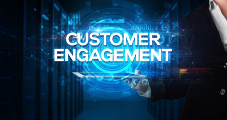Young business person working on tablet and shows the inscription: CUSTOMER ENGAGEMENT, business...