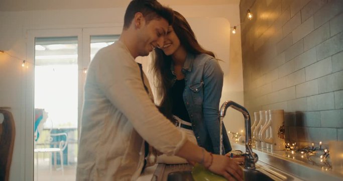 Young adult couple washing dishes together. Shot in slow motion