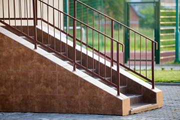 Concrete stairs covered with ceramic tiles with metal railings outdoors.