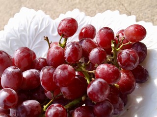 Red table grapes ready-to-eat on a white milk glass dish