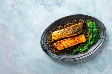 Roasted salmon with sesame seeds, wakame and wild black rice, top shot with a place for text