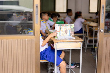 Unidentified children study in the classroom with open book.