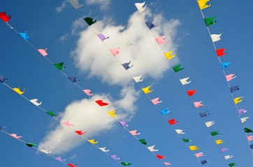 multicolored flags on blue sky background and white clouds. pink, yellow, red, white, blue, green