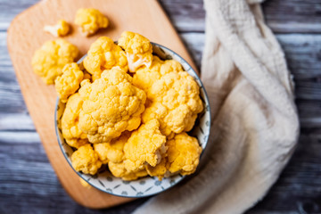 Choux fleur jaune en fleurettes dans un bol sur une table en bois
