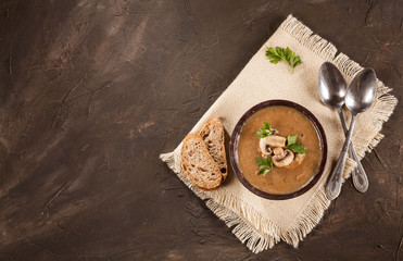 Delicious creamy mushroom soup with parsley and close-up on a dark background.