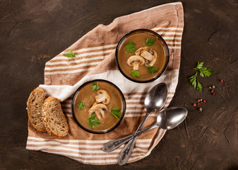 Delicious creamy mushroom soup with parsley and close-up on a dark background.