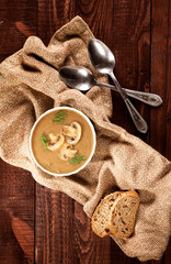 Delicious creamy mushroom soup with dill and close-up on a dark wooden background.