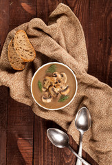 Delicious creamy mushroom soup with dill and close-up on a dark wooden background.