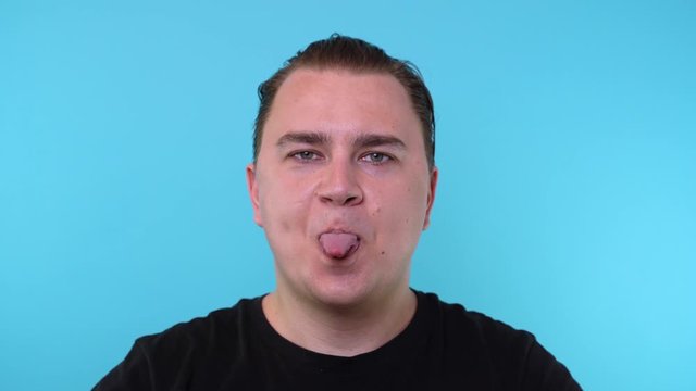 Caucasian man sticks out his tongue cut out on a blue background