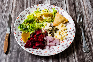 Assiette de salade composée avec dés de fromage betteraves échalotes graines de courge samoussa