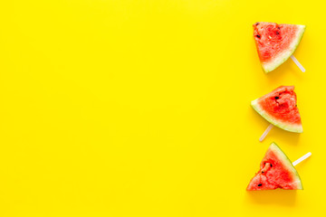 Cut watermelon on stick for break with fruit popsicle on yellow background top view mockup
