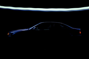 Fast business luxury prestige car lit in the dark