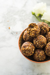 Energy protein balls with healthy ingredients on marble table. Home made with dates, peanut butter, flax and chia seeds, oats, almond and chocolate drops