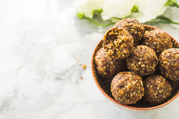 Energy protein balls with healthy ingredients on marble table. Home made with dates, peanut butter, flax and chia seeds, oats, almond and chocolate drops