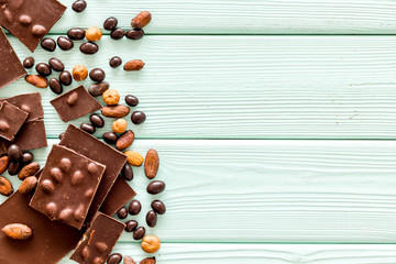 Cook homemade chocolate with bars, nuts, coffee beans on mint green wooden background top view mock up