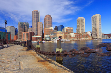 Boston skyline with skyscrapers reflections into the ocean and rusty chain on the foreground,...