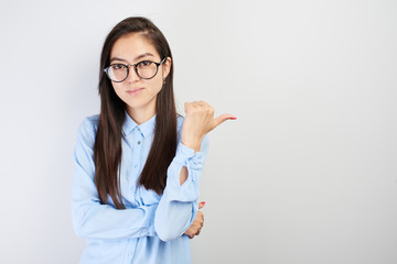 Asian Kazakh girl student with glasses shows finger on empty copy space, place for your...
