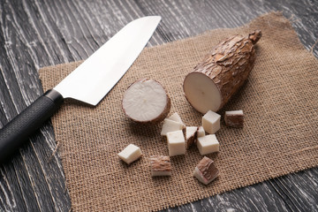Sliced yucca root on a sackcloth on a black wooden table with a knife