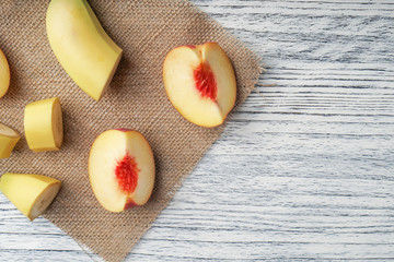 Slices of banana and peach spread on a sackcloth on a black wooden table