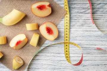 Slices of banana and peach spread out on a sack on a black wooden table with a centimeter