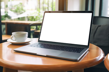 Mockup image of laptop computer with blank white desktop screen with coffee cup on wooden table