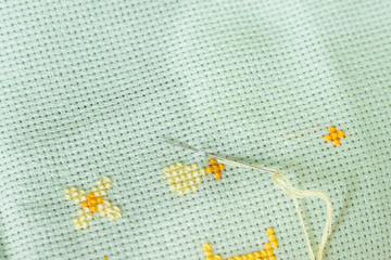 The process of working cross-stitch on canvas fabric.