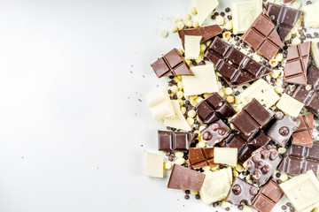 Assorted different types of chocolate. Broken pieces of dark, milk and white chocolate, with nuts, cooking chocolate, shavings. top view copy space