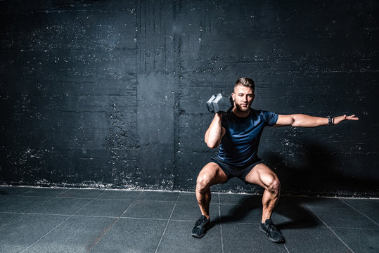 Young Strong Fit Muscular Sweaty Man With Big Muscles Strength Cross Workout Training With Dumbbells Weights In The Gym Dark Image With Shadows Real People