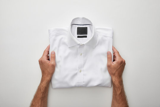 Cropped View Of Man Holding Folded Shirt On White Background