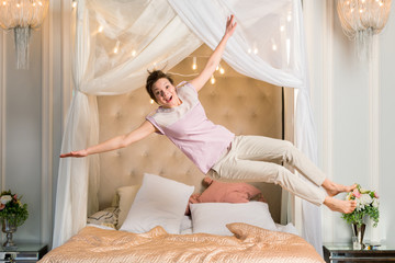 Happy woman jumping in bed