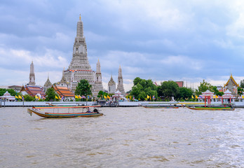 In Bangkok, The Wat Arun is old buddhist temple are located on the Chao Phraya river with Passenger ship in Thailand.