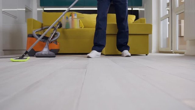 Picture of unrecognizable cleaning worker in blue uniform washing the kitchen floor