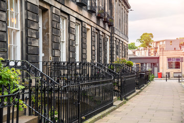 Old stone terraced houses with metal fences along a street at sunset. Edinburgh, Scotland, UK.