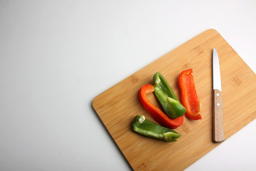 cut bell peper on wooden cutting board flat lay on white background